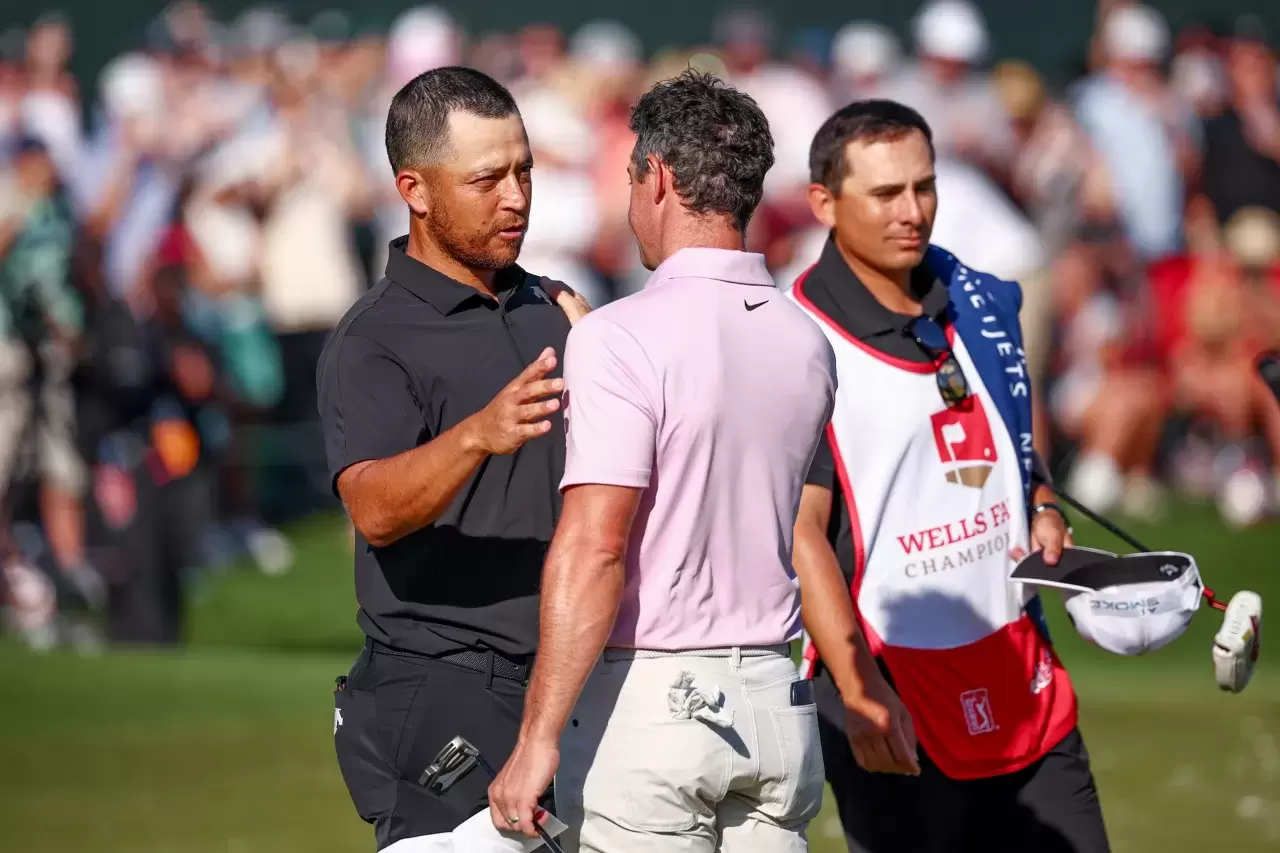 Xander Schauffele shakes hands with Rory McIlroy of Northern Ireland after McIlroy won the Wells Fargo Championship at Quail Hollow Club