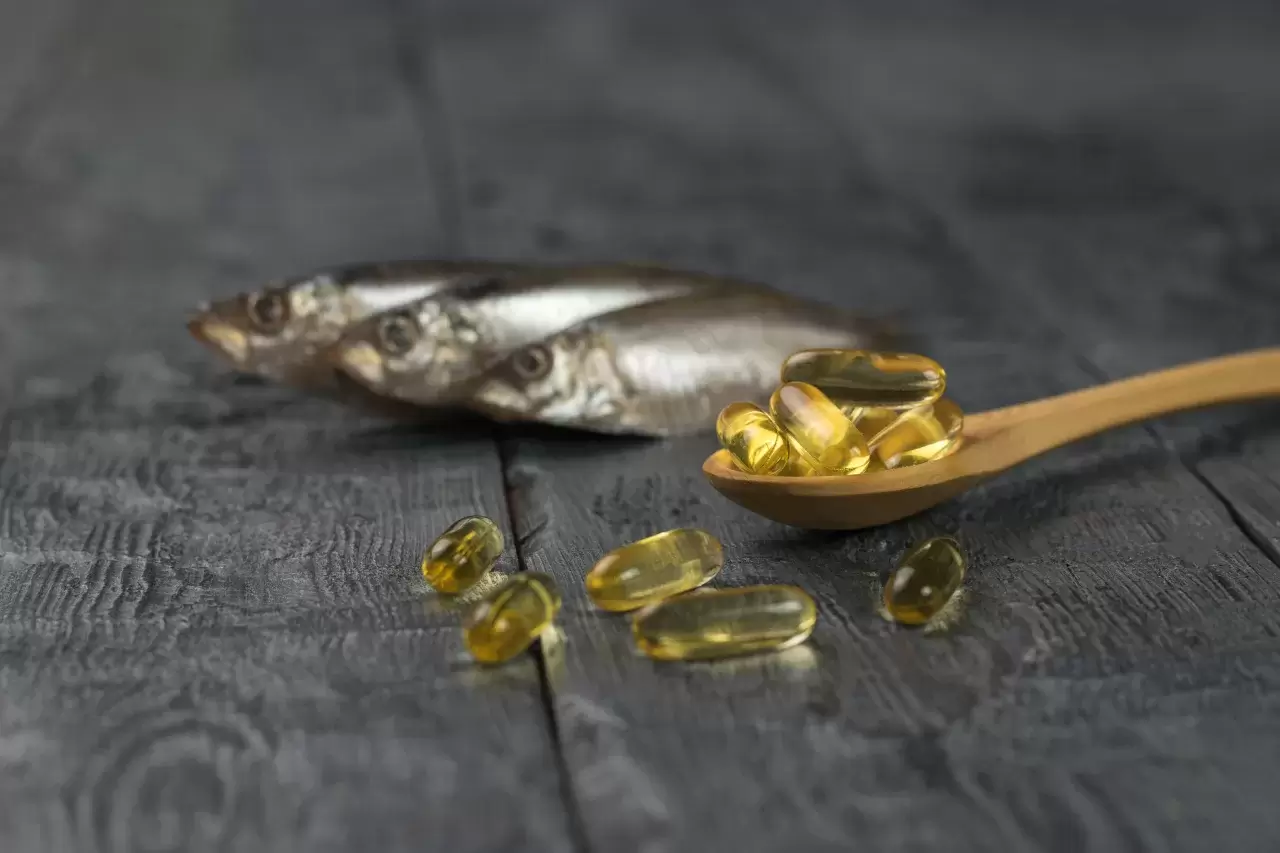 olzlöffel mit Fischölkapseln auf dem Hintergrund von drei Fischen auf einem Holztisch. Biologisch wirksamer Zusatzstoff