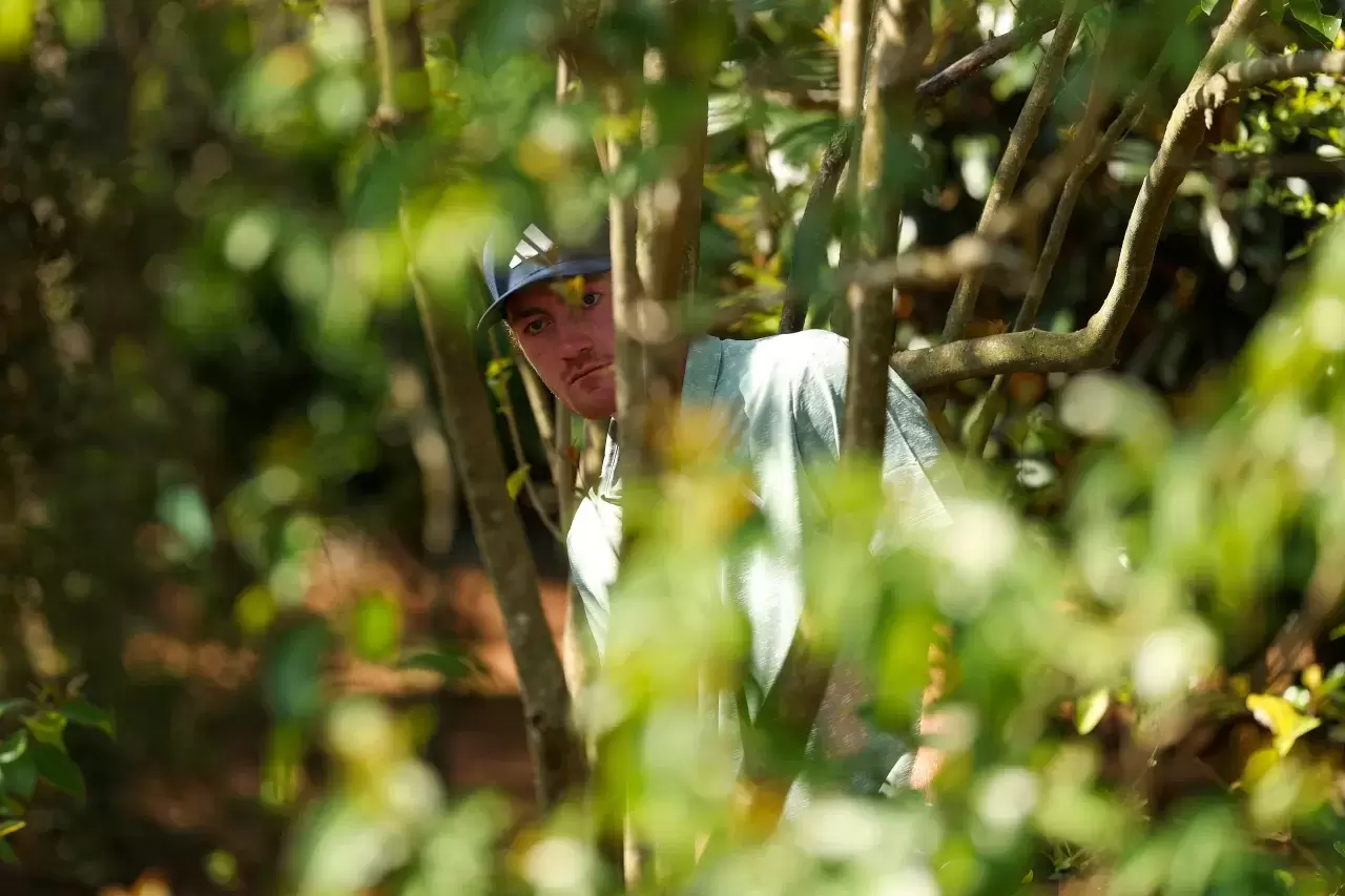 Nick Dunlap play a shot from the trees on the fifth hole during the first round of the 2025 Masters Tournament at Augusta National Golf Club