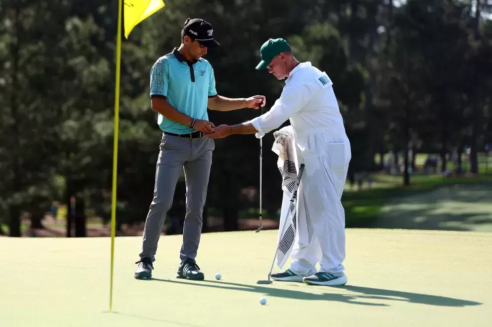 Joaquin Niemann of Chile talks with his caddie Gary Matthews on the seventh green during a practice round prior to the 2024
